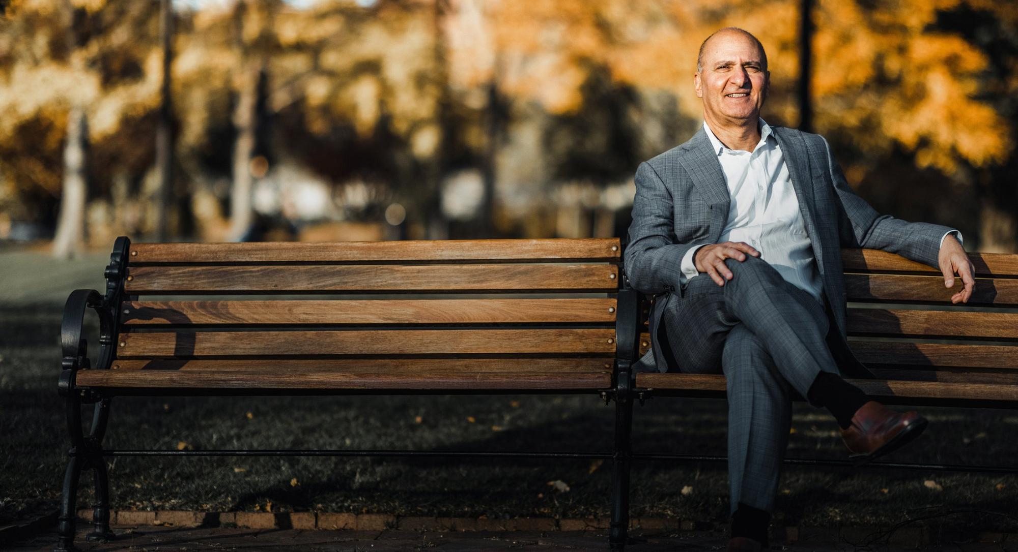 Dr. Russo - Boston Plastic Surgeon, sitting on a bench and smiling