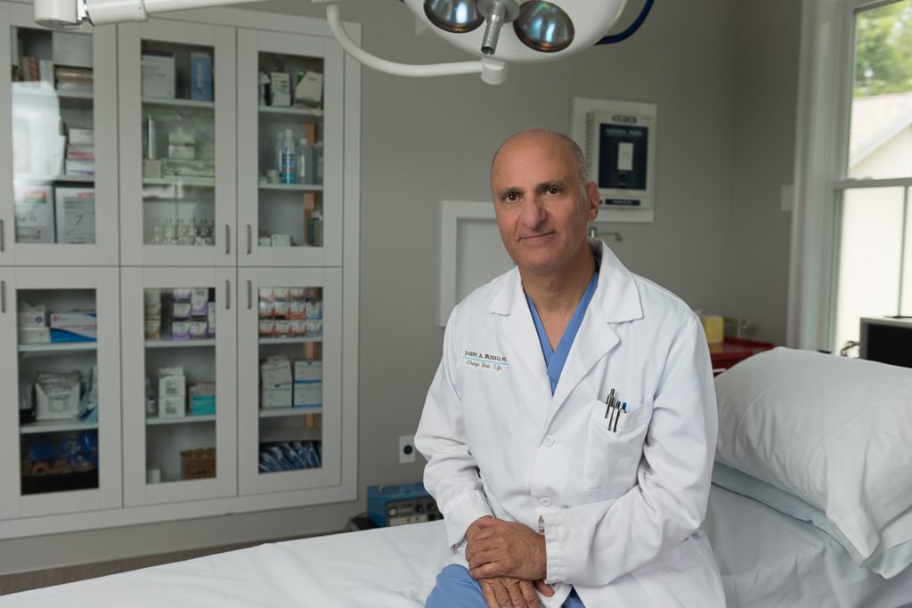 Dr. Russo - Boston plastic surgeon sitting on side of medical bed