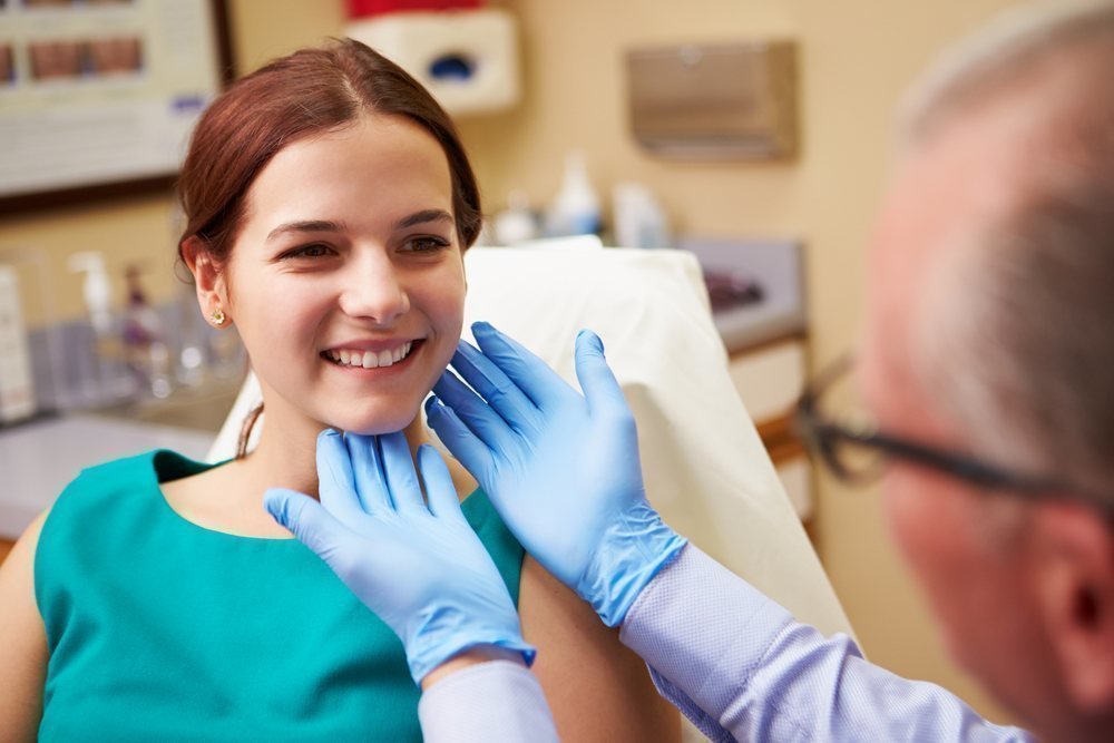 Female plastic surgery patient model smiling with doctor observing her face