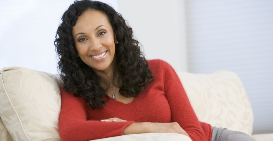 Woman sitting on couch wearing red sweater